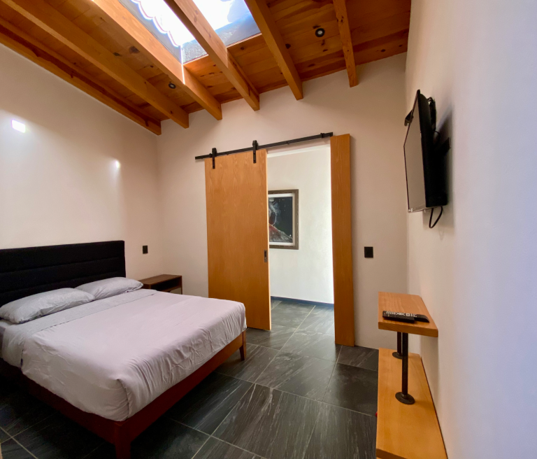 Recámara con cama matrimonial, TV y baño en el interior Recámara con cama matrimonial, TV y baño en el interior